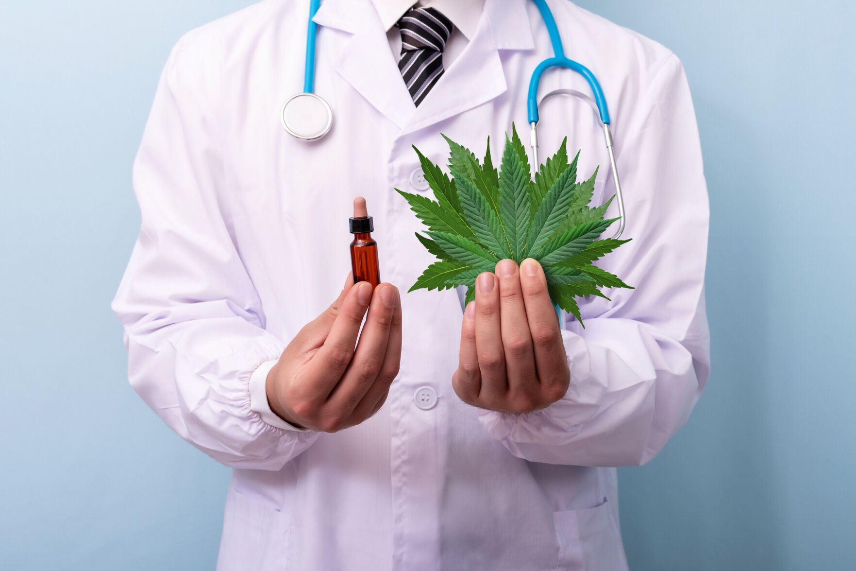Doctor hands holding cannabis leaves and oil. Doctor prescribing marijuana extract.